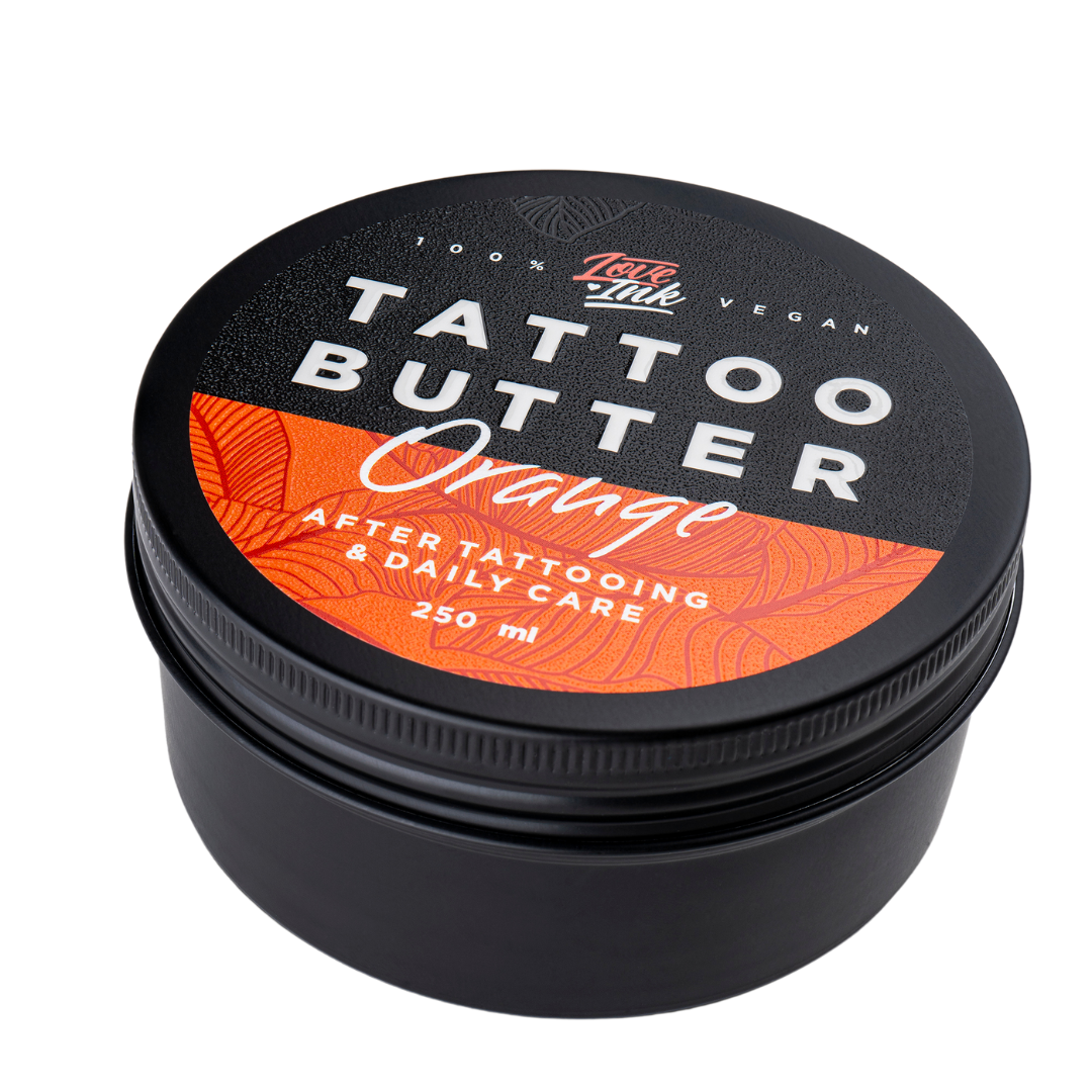 Close-up of a 250ml jar of Tattoo Butter Orange by LoveInk. The product features a black and orange design, emphasizing its use for after tattooing and daily care.