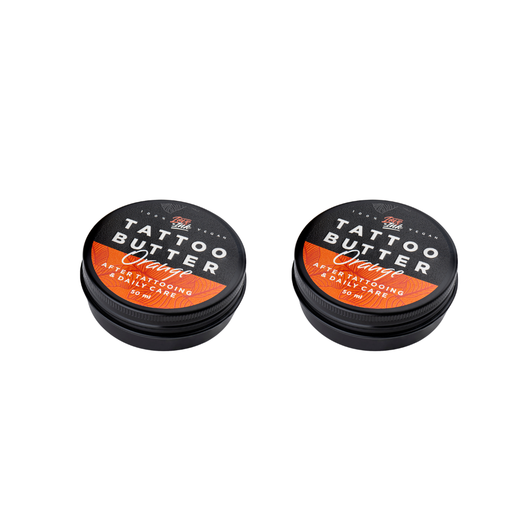 Two tins of Love Ink Tattoo Butter Orange on a transparent background. Both tins are labeled 'Tattoo Butter Orange' for after tattooing and daily care, and each contains 50 ml.