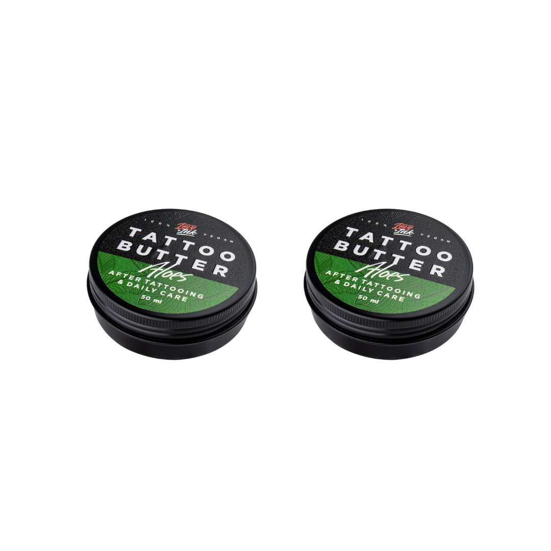 Two tins of Love Ink Tattoo Butter on a transparent background. Both tins are labeled 'Tattoo Butter Aloes' with an green design