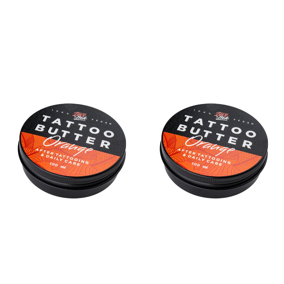 Two tins of Love Ink Tattoo Butter on a transparent background. Both tins are labeled 'Orange' with an orange design.